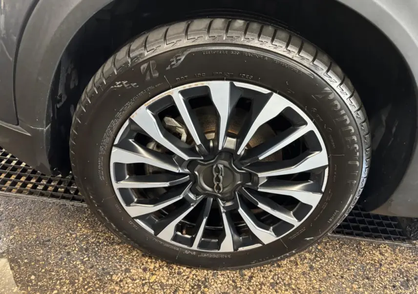 Gros plan sur la jante 16 pouces classique gris et noir de la FIAT 500X MY23, avec pneu Bridgestone visible.