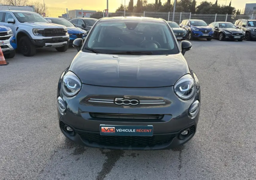 Vue avant d'une FIAT 500X MY23 gris, avec phares ronds et calandre distinctive, stationnée en extérieur.