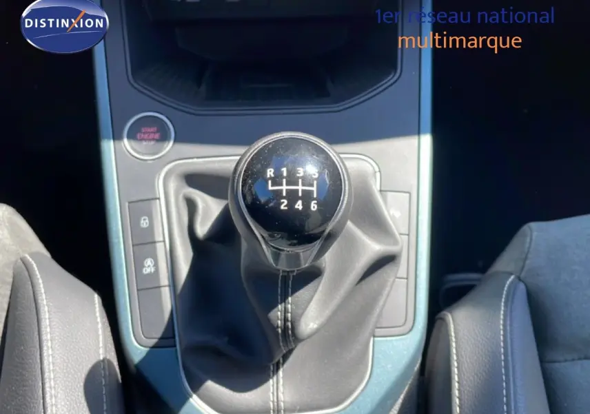 Gros plan sur le levier de vitesse manuel noir du SEAT Arona 2025, entouré de la console centrale bleu métallisé.