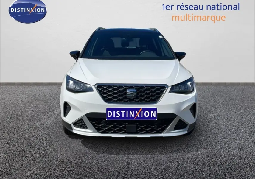 Vue avant d'un SEAT Arona 2025 blanc avec toit noir, calandre noire et phares LED, sur fond neutre.