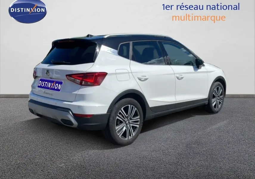 Vue 3/4 arrière droite d’un SEAT Arona blanc avec toit noir, jantes alliage et détails noirs contrastants.
