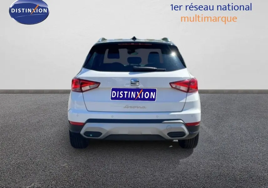 Vue arrière d'une SEAT Arona 2025 blanche avec toit noir, mettant en valeur ses feux arrière anguleux et son pare-chocs contrasté.