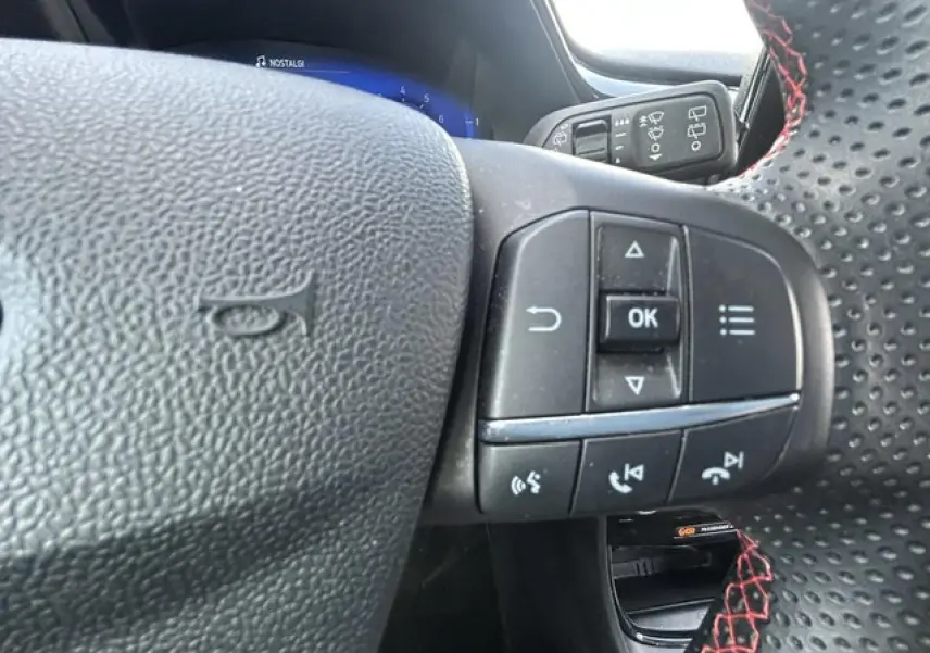 Gros plan sur les commandes au volant perforé noir avec surpiqûres rouges du Ford Puma ST Line 2022.