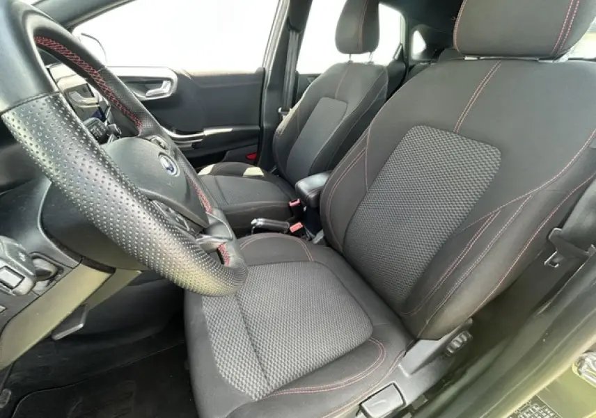 Intérieur Ford Puma ST Line 2022 vu côté conducteur, sièges tissu noir avec surpiqûres rouges et volant perforé.
