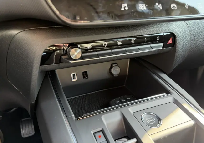 Détail de la console centrale noire du Citroën C5 Aircross 2025 avec boutons de commande et prise 12V vus de côté droit