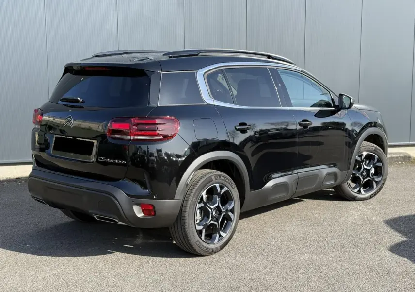 Vue 3/4 arrière droite du Citroën C5 Aircross noir Perla avec jantes alliage bi-ton et barres de toit noires.