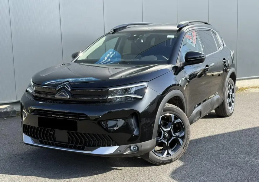 Vue 3/4 avant d'un Citroën C5 Aircross 2025 noir Perla avec jantes alliage bi-ton et barres de toit noires.