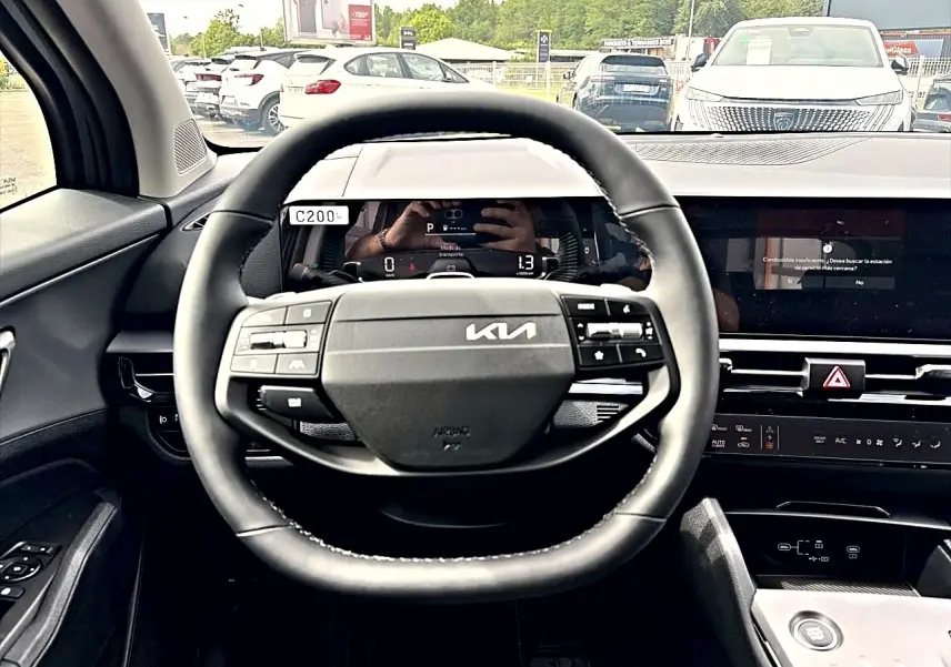 Vue intérieure centrée sur le volant noir du Kia Sportage 1.6 hybride 239 avec tableau de bord numérique et écran tactile.