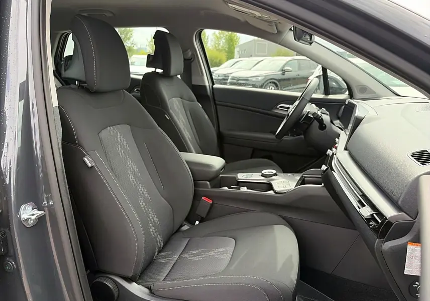 Vue intérieure côté conducteur du Kia Sportage 1.6 hybride gris eclipse, montrant sièges et console centrale moderne.