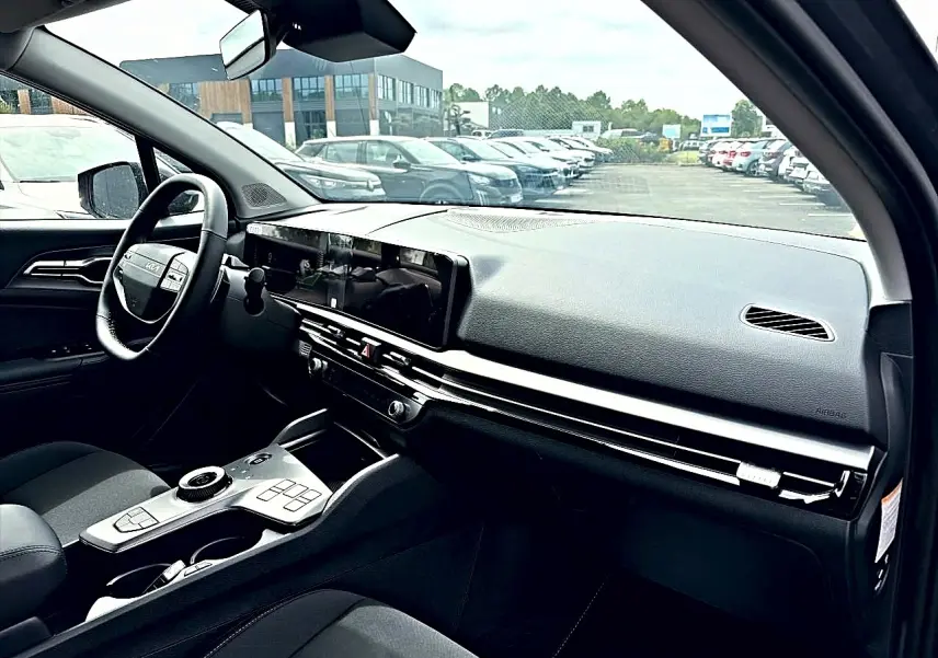 Vue intérieure côté conducteur du tableau de bord et console centrale du KIA Sportage 1.6 hybride gris eclipse 2026, volant cuir multifonction.