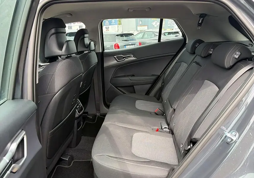 Vue intérieure côté droit de la banquette arrière grise du Kia Sportage 1.6 hybride 239 active avec appuie-têtes et porte ouvert.