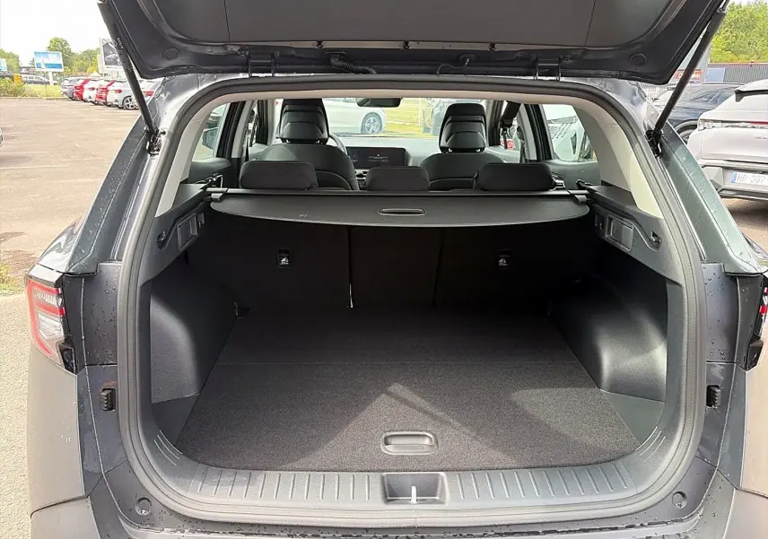 Coffre ouvert vu de l'arrière du Kia Sportage gris eclipse 2026, montrant l'espace de chargement et la tablette cache-bagages.