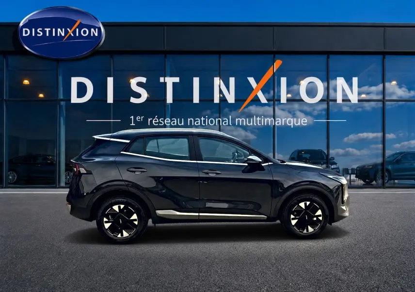 Vue de profil côté gauche du KIA SPORTAGE 1.6 hybride 239 Active gris eclipse, avec jantes alu et barres de toit visibles.