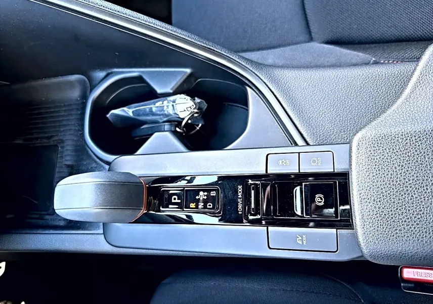 Vue plongeante sur la console centrale noire du Toyota C-HR gris, avec levier de vitesse automatique et accoudoir.