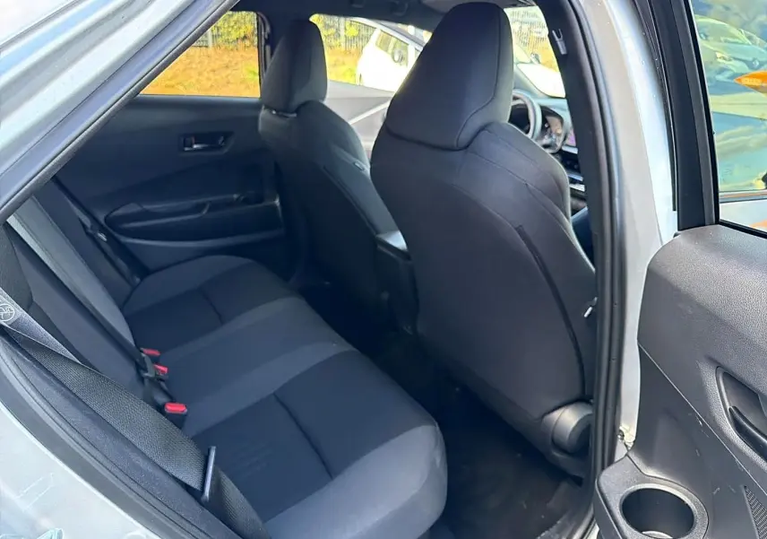 Vue intérieure côté gauche sur la banquette arrière grise du Toyota C-HR 1.8 hybride 2025 avec portière ouverte.