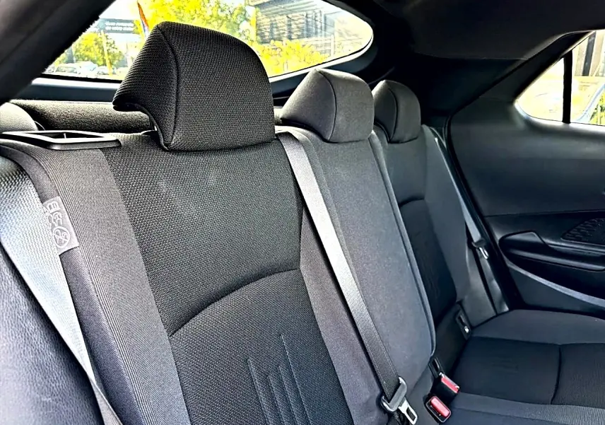 Vue intérieure côté droit des sièges arrière gris foncé du Toyota C-HR 1.8 hybride 2025 avec ceintures de sécurité visibles.