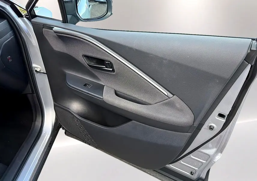 Vue intérieure de la porte avant gauche gris foncé du Toyota C-HR 1.8 hybride 2025 avec poignée et commande de vitre.