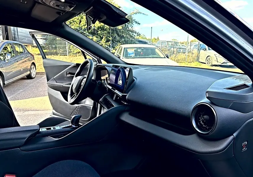 Intérieur avant droit du Toyota C-HR gris 2025, tableau de bord moderne avec écran tactile et volant multifonction.