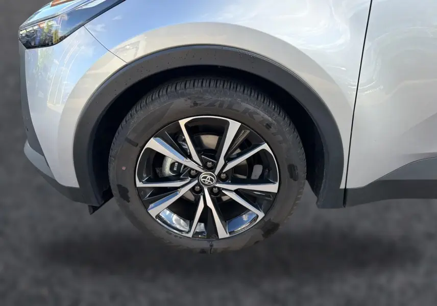 Gros plan sur la roue avant gauche du Toyota C-HR gris 2025 avec jante alliage noire et argentée.
