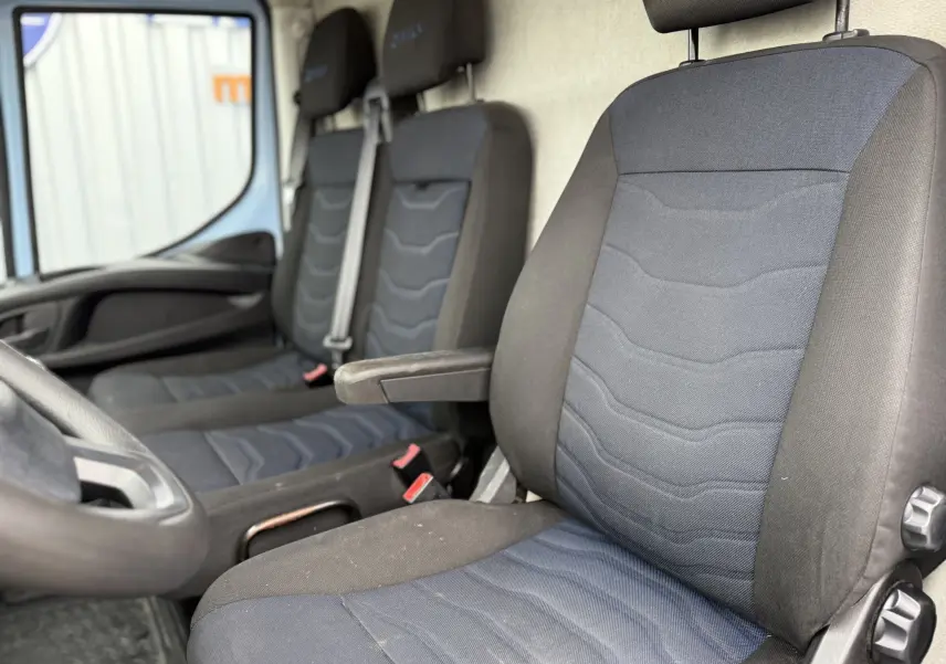 Vue intérieure sur les sièges avant tissu bleu et noir de l’IVECO Daily Fourgon 2017, avec accoudoir côté droit.