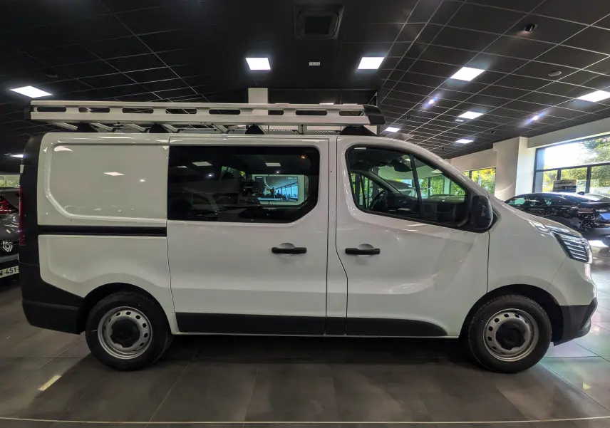 Profil droit du Renault Trafic Cabine Approfondie blanc minéral 2023 avec galerie de toit en intérieur showroom.