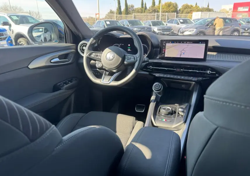 Vue intérieure de l'Alfa Romeo Tonale 2025, tableau de bord et volant sport avec écran tactile et console centrale moderne.