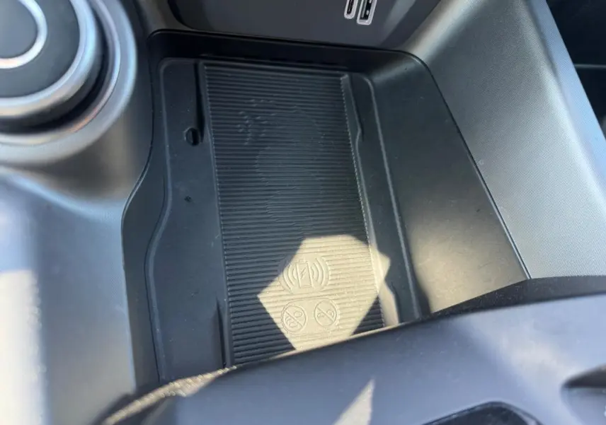 Gros plan sur la console centrale noire de l'Alfa Romeo Tonale 2025, avec zone de charge sans fil et ports USB visibles.