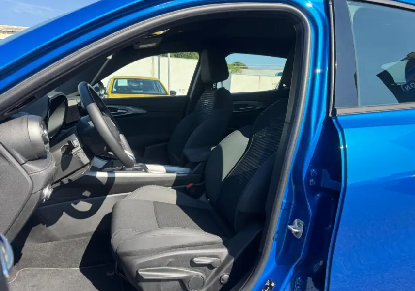 Vue intérieure côté conducteur de l'Alfa Romeo Tonale bleu foncé 2025, avec sièges sport et volant multifonction.