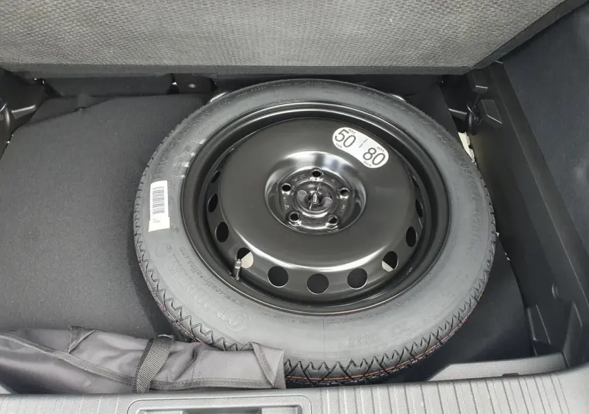 Roue de secours temporaire noire dans le coffre du Renault Captur 2026, vue plongeante sur le pneu.