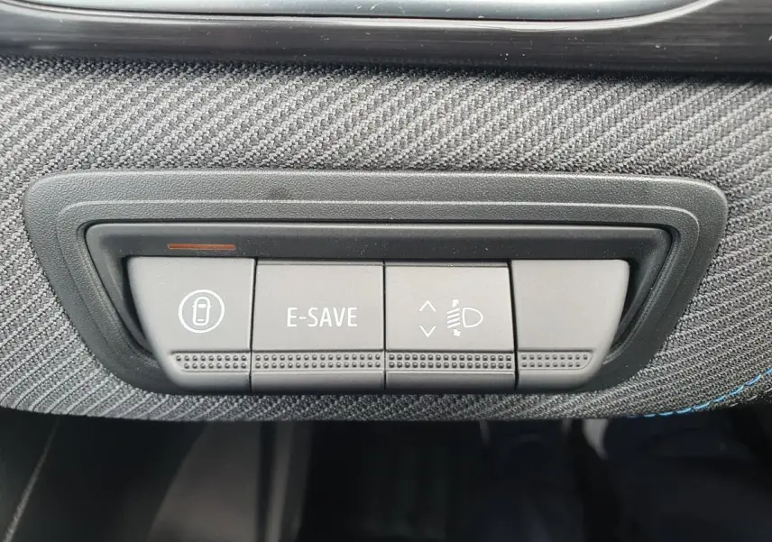 Gros plan sur les boutons de commande E-SAVE et réglage des phares dans l’habitacle du Renault Captur bleu Iron.