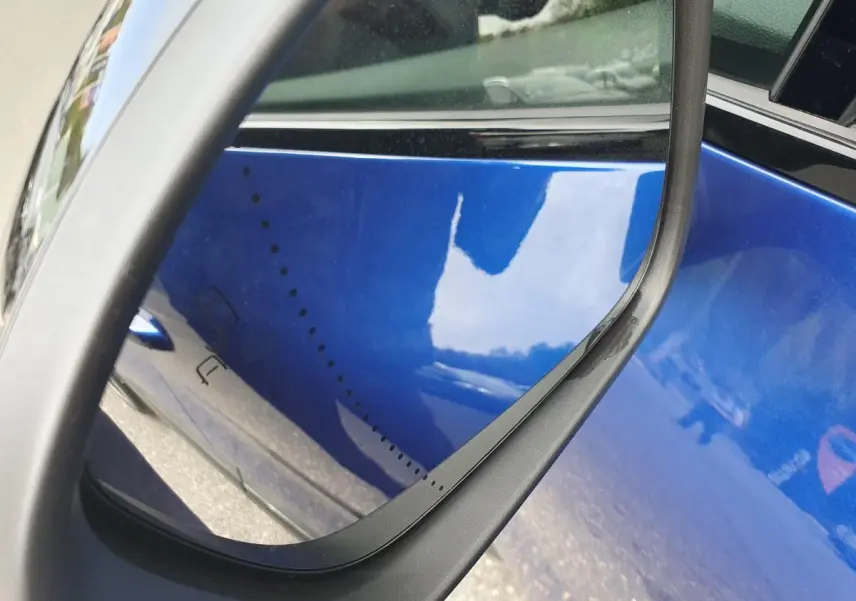 Gros plan sur le rétroviseur côté droit d’un Renault Captur bleu Iron avec reflet de la carrosserie métallique.