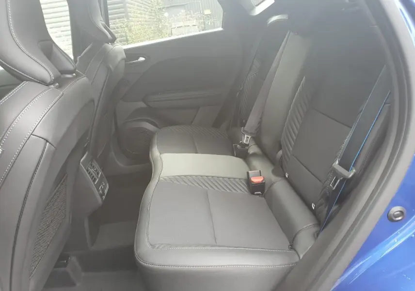 Vue intérieure arrière côté droit du Renault Captur bleu Iron, sièges noirs avec surpiqûres bleues et prises USB visibles.
