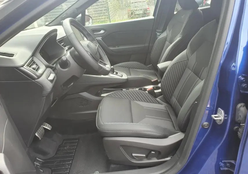 Vue intérieure côté conducteur du Renault Captur bleu iron 2026, sièges noirs et tableau de bord moderne.