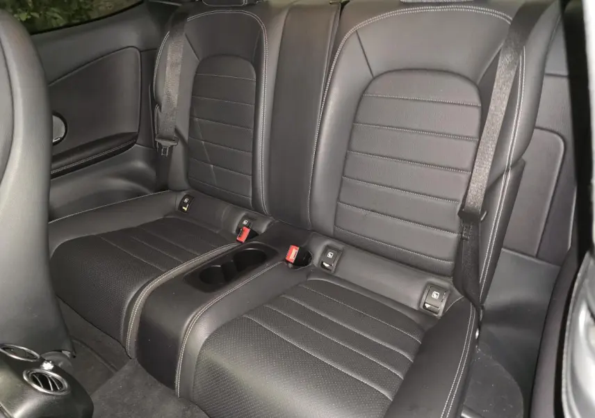 Vue intérieure sur la banquette arrière noire en similicuir avec ceintures et accoudoir central de la Mercedes Classe C Coupé.