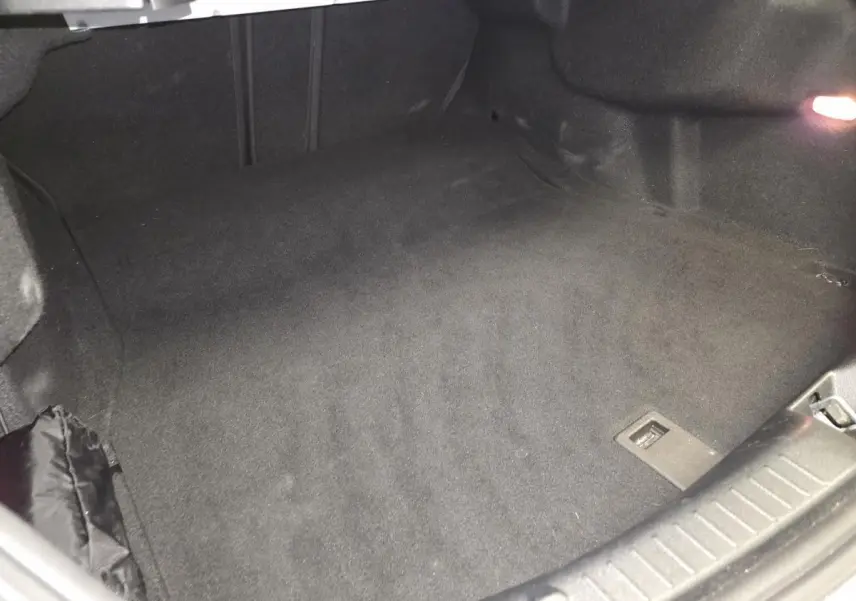 Coffre ouvert de Mercedes Classe C Coupé blanc, vue intérieure montrant le tapis noir et l'éclairage latéral.