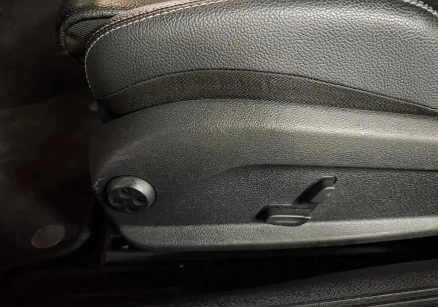 Détail du côté gauche d’un siège avant noir en cuir avec commandes électriques sur une Mercedes Classe C Coupé blanc.