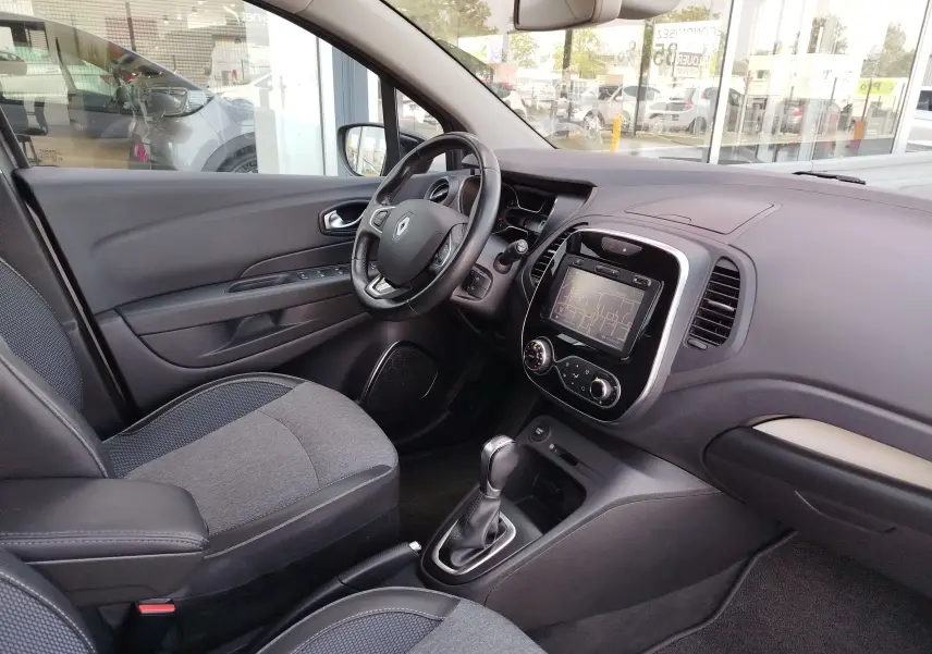 Vue intérieure côté conducteur du Renault Captur 2018, tableau de bord gris avec écran tactile et volant multifonction.