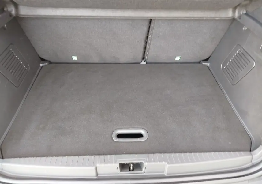 Coffre spacieux et propre du Renault Captur gris Cassiopée, vu de l'arrière avec plancher plat et compartiments latéraux.