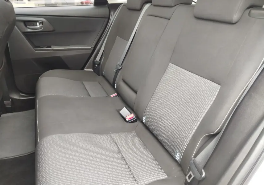 Vue intérieure des sièges arrière gris foncé de la Toyota Auris HSD 136h SkyBlue, avec ceinture de sécurité et porte côté gauche visible.