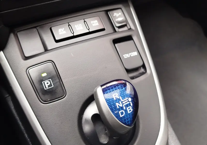 Gros plan sur le levier de vitesses bleu et les boutons de modes de conduite du Toyota Auris HSD 136h gris aluminium.