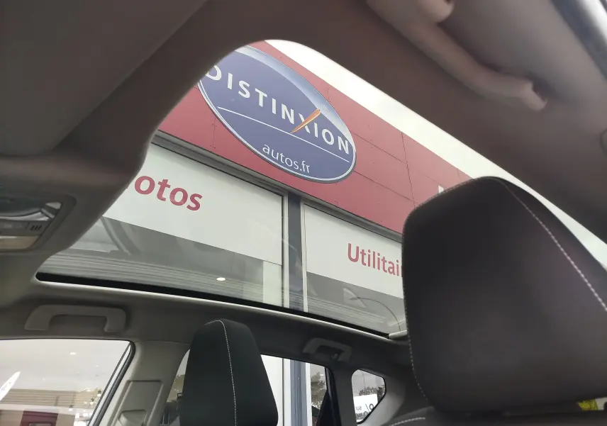 Vue intérieure du toit ouvrant panoramique et appuie-tête avant droit de la Toyota Auris HSD 136h gris aluminium de 2015.