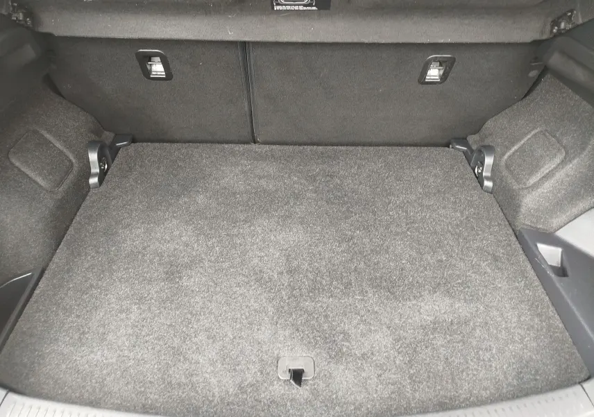 Vue intérieure du coffre spacieux et tapissé de moquette grise de la Toyota Auris HSD 136h SkyBlue 2015.