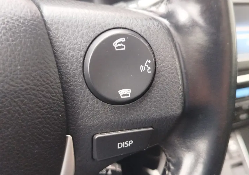 Gros plan sur les boutons de commande d’appel et affichage au volant en cuir noir d’une Toyota Auris HSD 136h gris aluminium.