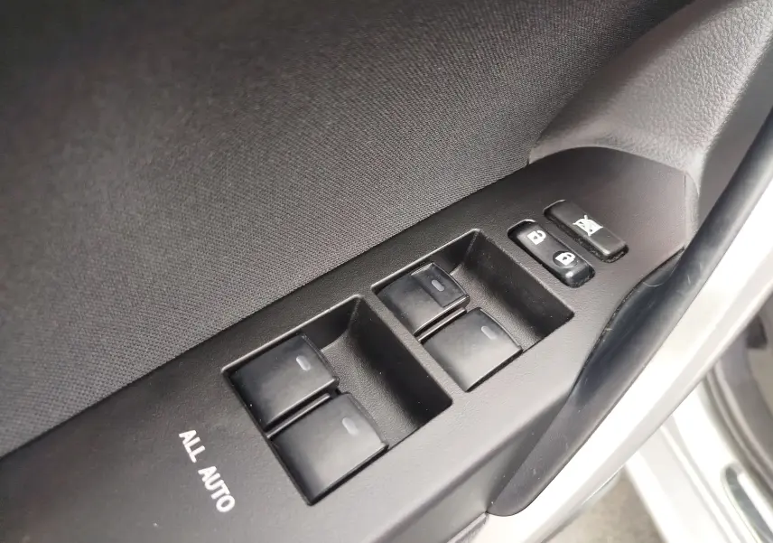 Gros plan sur les commandes de lève-vitres et verrouillage sur la porte côté conducteur d'une Toyota Auris gris aluminium.