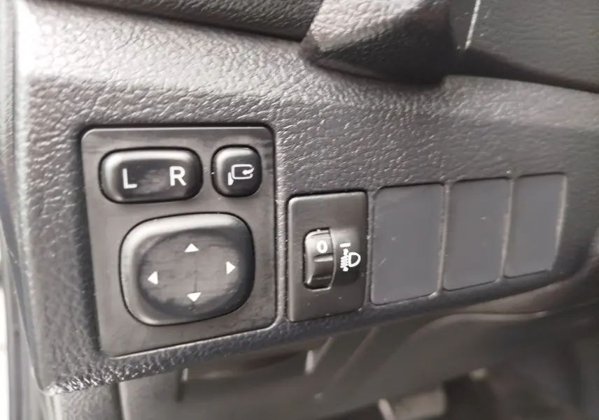 Gros plan sur les commandes de réglage des rétroviseurs et de l’éclairage, intérieur noir de la Toyota Auris HSD 136h 2015.