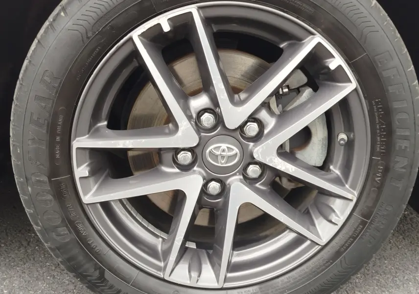 Gros plan sur la jante alliage gris foncé avec logo Toyota au centre d’un pneu Goodyear sur Toyota Auris HSD 136h.