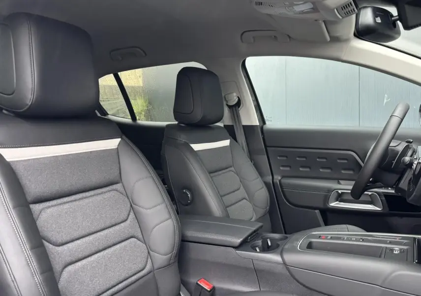 Vue intérieure côté droit du Citroën C5 Aircross 2025, sièges Advanced Comfort noirs avec insert tissu gris et accoudoir central.
