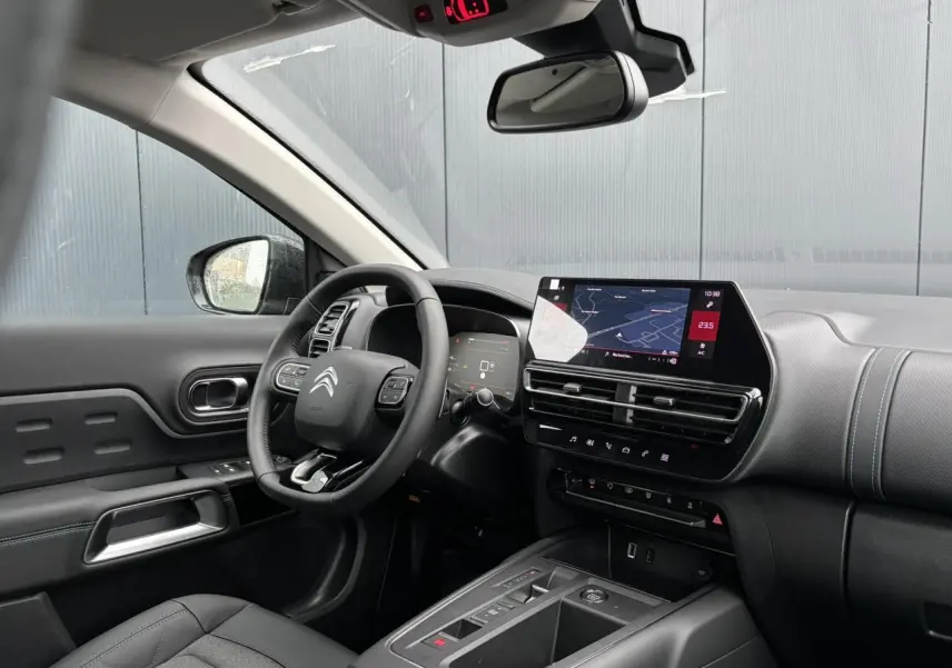 Vue intérieure côté conducteur du Citroën C5 Aircross 2025, tableau de bord noir avec écran tactile et volant multifonction.