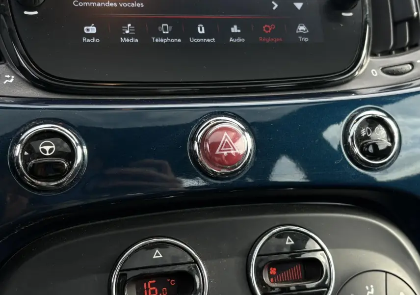 Gros plan sur la console centrale bleu Dipinto de la Fiat 500 Hybrid 2024 avec commandes clim et bouton de warning rouge.