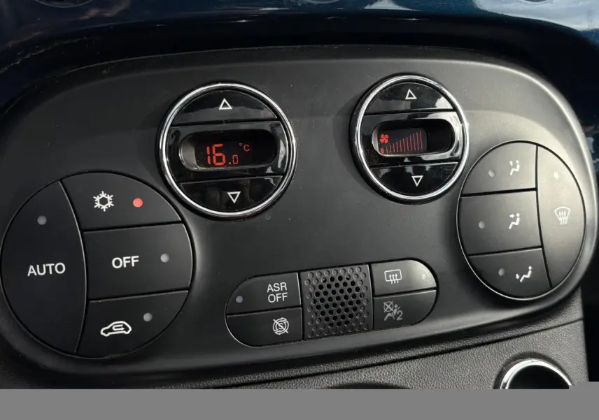 Gros plan sur la commande de climatisation digitale de la Fiat 500 Hybrid 70, affichant 16°C, avec boutons noirs et détails rouges.